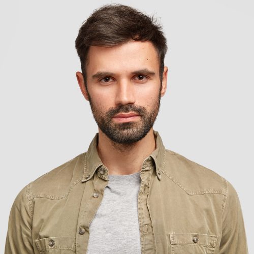 confident-bearded-man-with-dark-hair-has-serious-facial-expression-thinks-about-future-job-dressed-fashionable-shirt-min